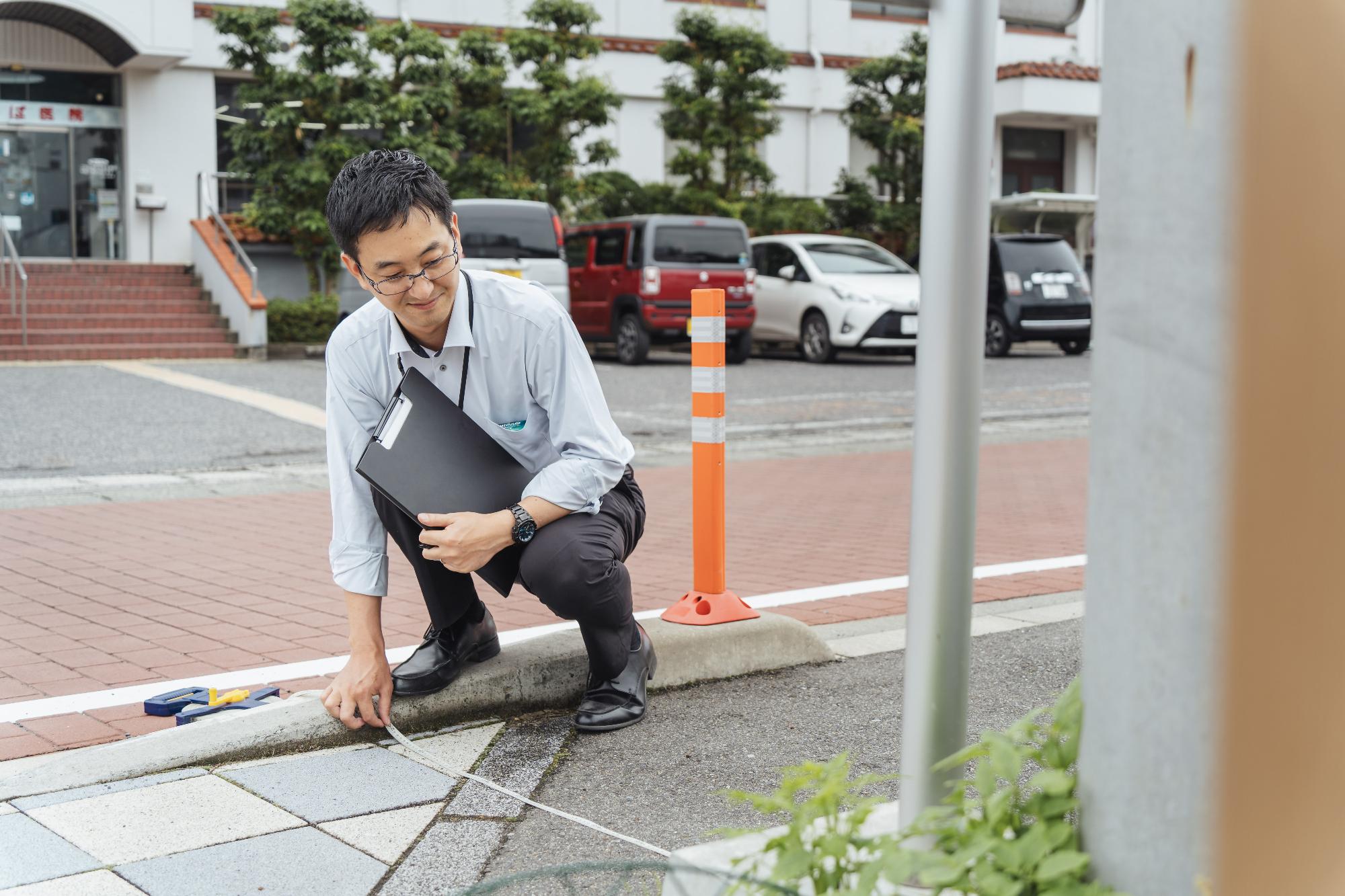 バス停近くの道路の幅員を計測する小池さん