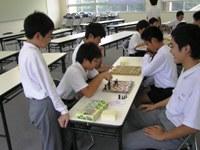小学生と中学生が囲碁で対決している写真