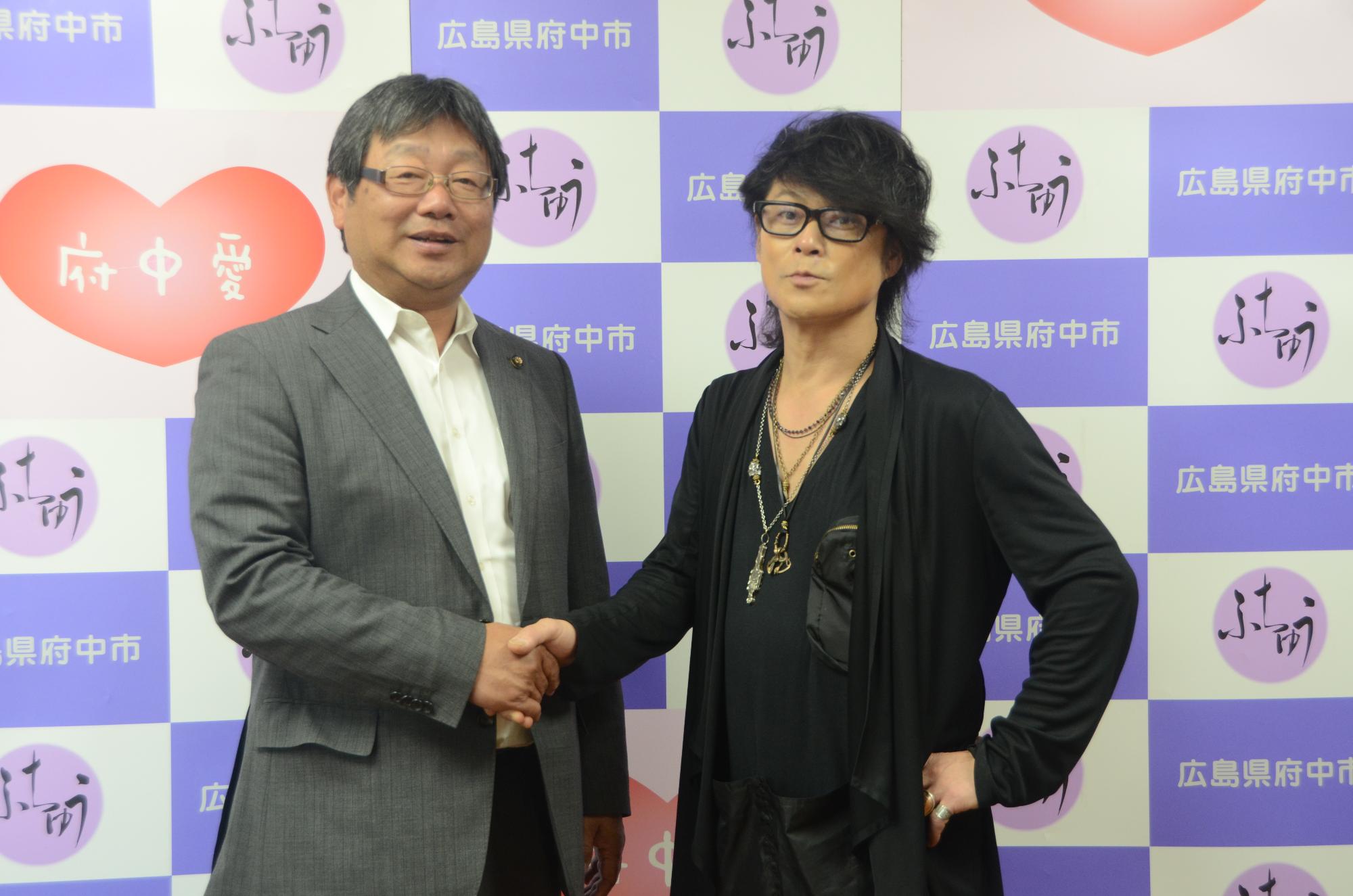 向かって左側の小野市長と向かって右側の森友嵐士さんが握手をしている写真です。